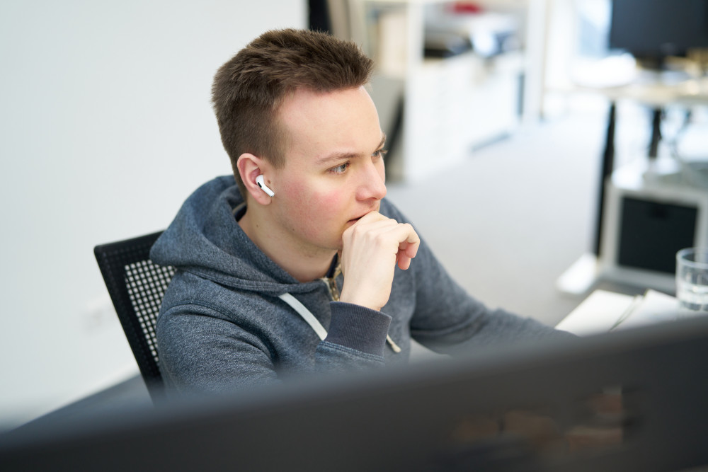 Niklas sitzt vor dem Computer und tut so, als würde er total konzentriert bei der Arbeit sein