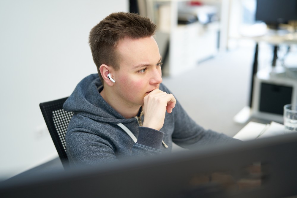 Niklas sitzt vor dem Computer und tut so, als würde er total konzentriert bei der Arbeit sein