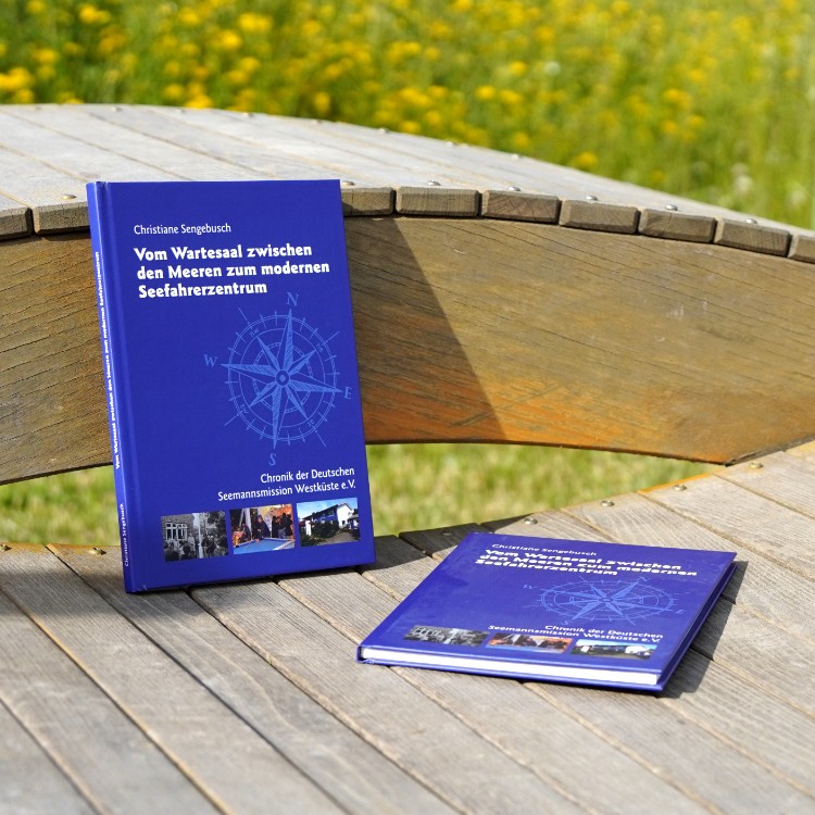 Zwei Exemplare der Chronik der Seemannsmission Brunsbüttel liegen auf einer Holzbank