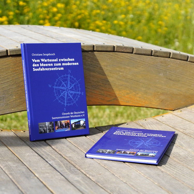 Zwei Exemplare der Chronik der Seemannsmission Brunsbüttel liegen auf einer Holzbank