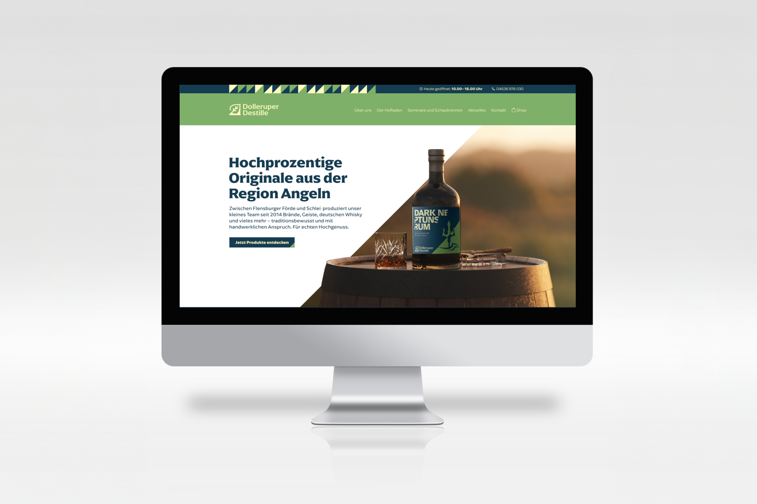 Mockup der Startseite einer Website auf einem Computermonitor. Neben der Überschrift „Hochprozentige Originale aus der Region Angeln“ steht eine Rumflasche auf einem Holzfass.